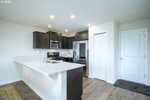 kitchen featuring a breakfast bar area, light wood-style flooring, stainless steel appliances, a peninsula, and light countertops