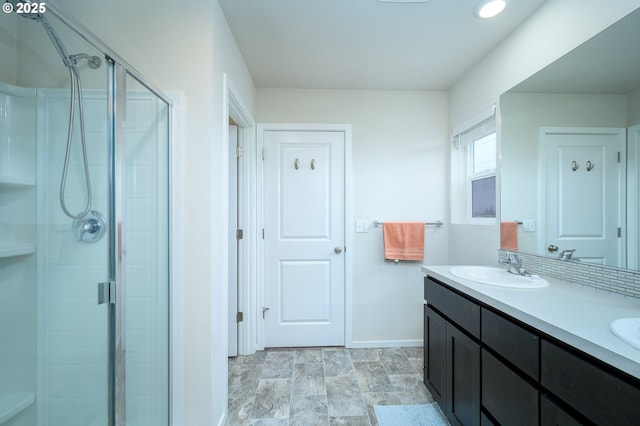 full bathroom featuring a stall shower, a sink, baseboards, and double vanity