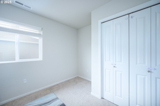 unfurnished bedroom with a closet, visible vents, and light colored carpet