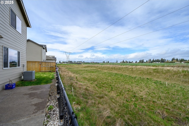 view of yard with a rural view, fence, and central AC