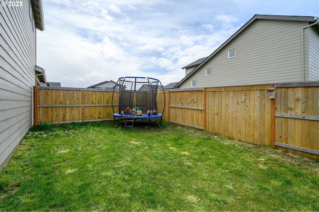 view of yard featuring a trampoline and a fenced backyard