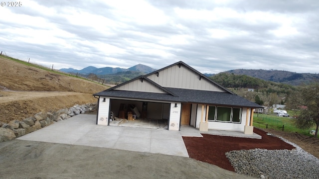 view of front of property featuring concrete driveway, an attached garage, a mountain view, and roof with shingles