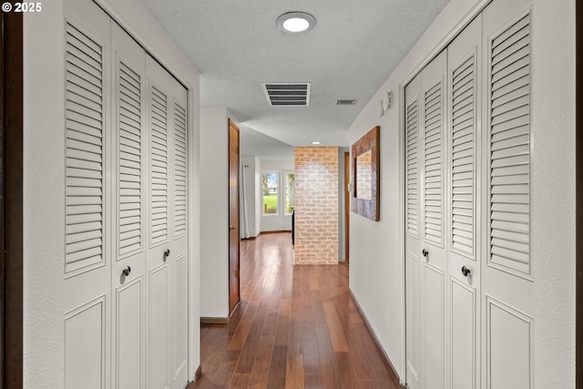 hallway featuring dark wood-type flooring and a textured ceiling