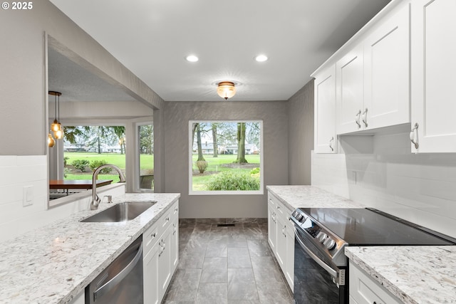 kitchen featuring appliances with stainless steel finishes, sink, white cabinets, and decorative light fixtures