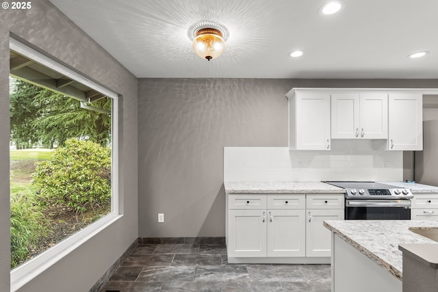 kitchen featuring backsplash, stainless steel electric range oven, light stone countertops, and white cabinets