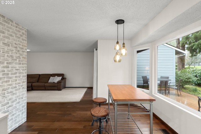 dining room featuring dark wood-type flooring and a textured ceiling