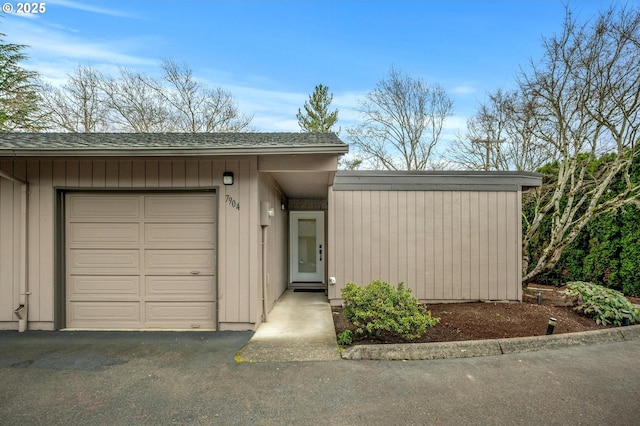 view of front of home featuring a garage, driveway, and a shingled roof