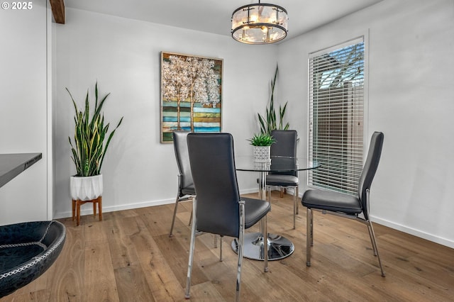 dining area featuring baseboards, hardwood / wood-style floors, and an inviting chandelier