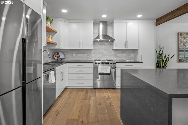 kitchen featuring open shelves, appliances with stainless steel finishes, a sink, wall chimney range hood, and modern cabinets