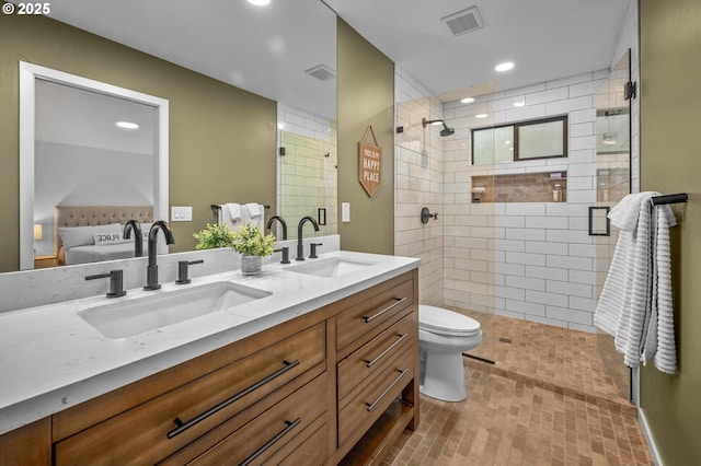 bathroom featuring visible vents, a tile shower, and a sink