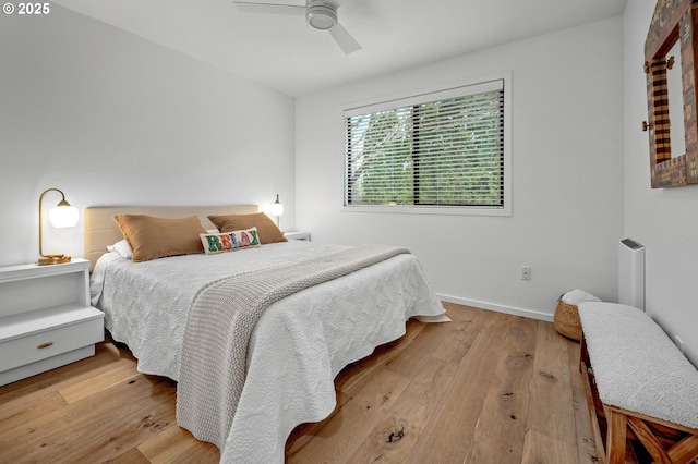 bedroom with hardwood / wood-style floors, a ceiling fan, and baseboards