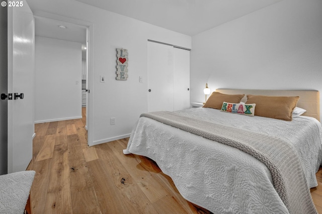 bedroom with a closet, baseboards, and light wood finished floors