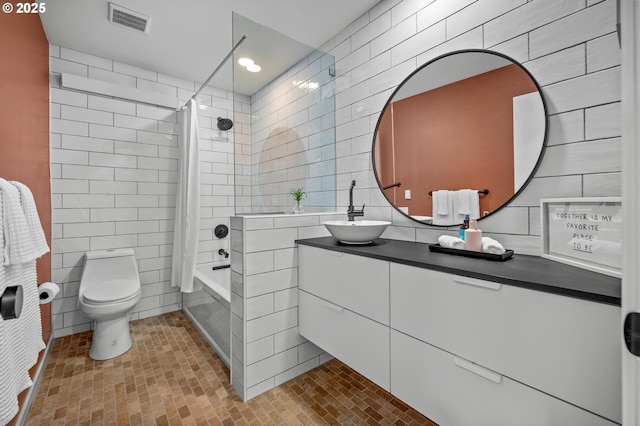 full bathroom with visible vents, toilet, shower / bathtub combination with curtain, vanity, and tile walls