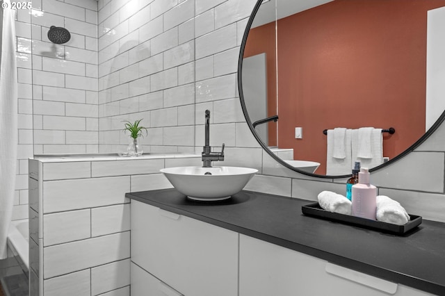 full bathroom featuring tiled shower, backsplash, vanity, and tile walls