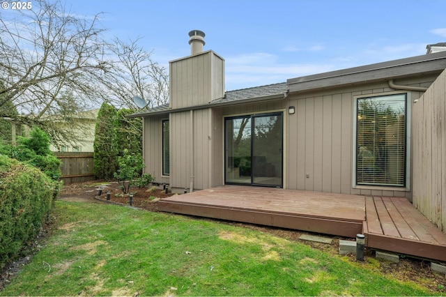 rear view of property featuring a lawn, a chimney, roof with shingles, fence, and a deck