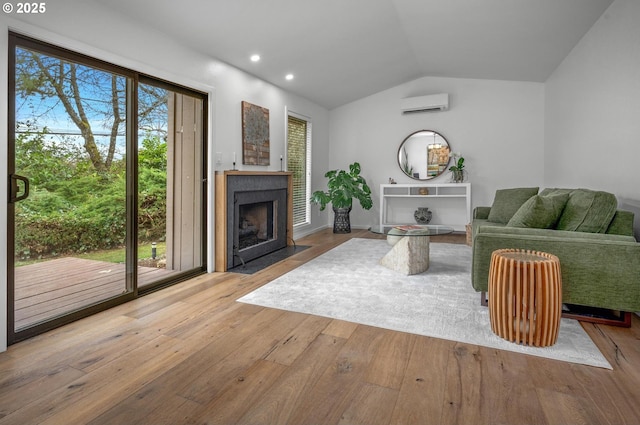 living room with lofted ceiling, recessed lighting, a fireplace with flush hearth, an AC wall unit, and hardwood / wood-style floors