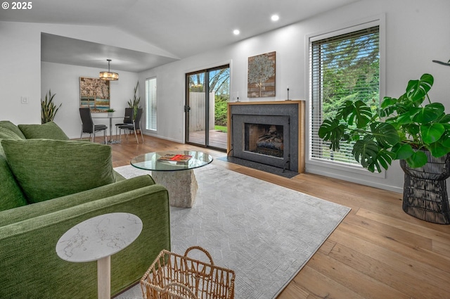 living room with lofted ceiling, hardwood / wood-style flooring, recessed lighting, a fireplace with flush hearth, and baseboards