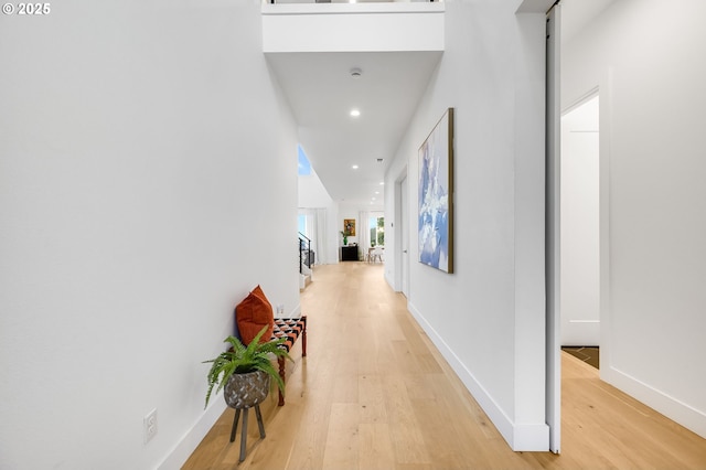 hallway featuring light wood finished floors, baseboards, and recessed lighting