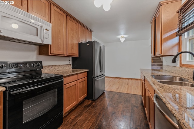 3116 NE 108th Ave, Portland, OR 97220 - kitchen with stainless steel appliances, a sink, dark wood-type flooring, light stone countertops, and brown cabinetry