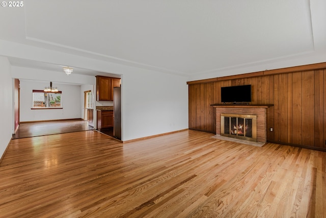 3116 NE 108th Ave, Portland, OR 97220 - unfurnished living room featuring a chandelier, a fireplace, light wood finished floors, and baseboards