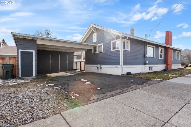 view of home's exterior with driveway, an attached carport, and a chimney