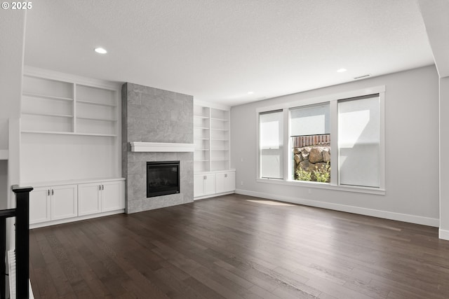 16706 NW Crossvine St, Portland, OR 97229 - unfurnished living room featuring a textured ceiling, dark wood-style floors, a tiled fireplace, baseboards, and recessed lighting