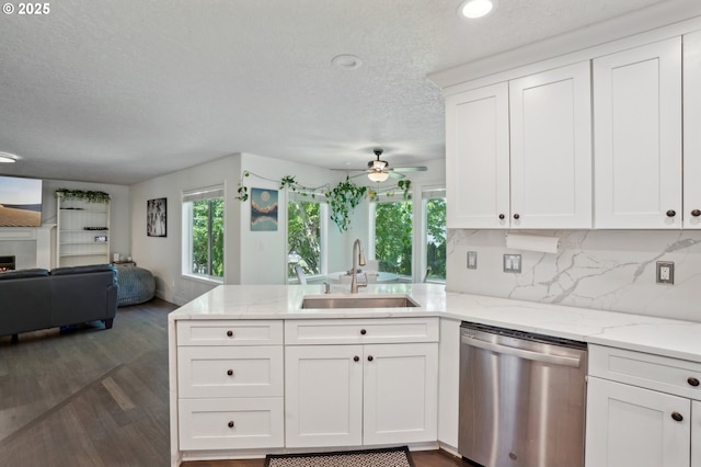 kitchen featuring dishwasher, a sink, open floor plan, a peninsula, and a textured ceiling