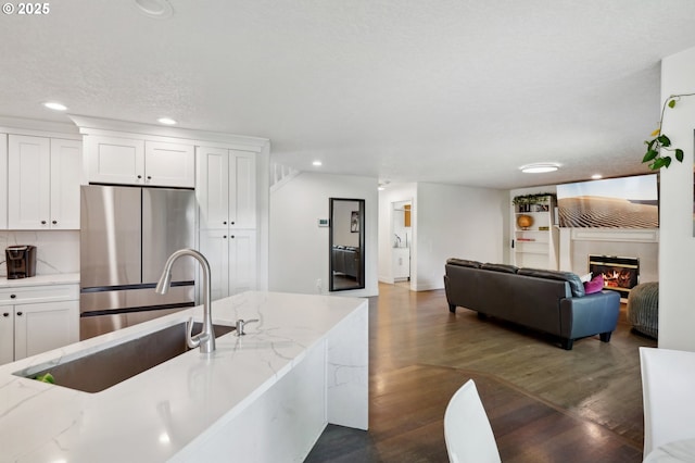 kitchen featuring freestanding refrigerator, white cabinetry, dark wood-style floors, recessed lighting, and a sink