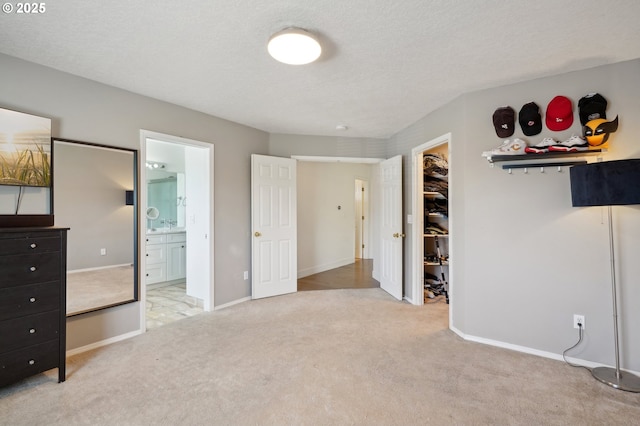 unfurnished bedroom with carpet floors, a spacious closet, ensuite bathroom, and baseboards