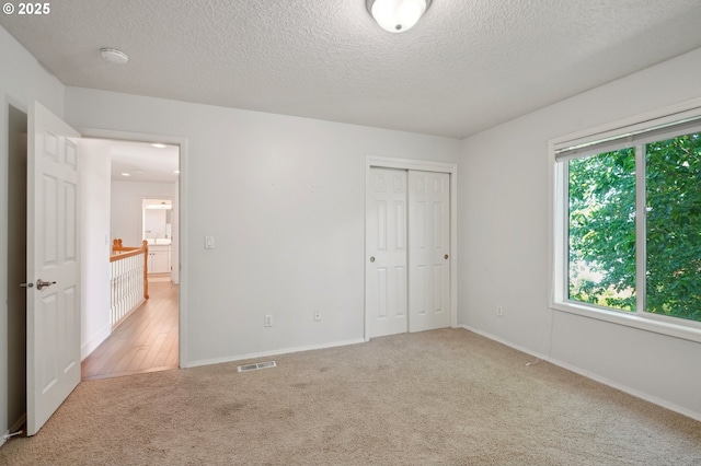 unfurnished bedroom with carpet, a textured ceiling, a closet, and baseboards