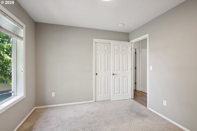 unfurnished bedroom featuring carpet flooring, baseboards, and a closet