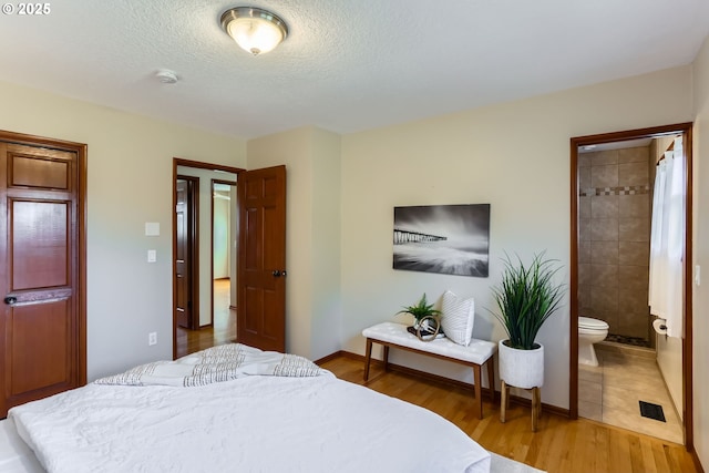 bedroom featuring hardwood / wood-style flooring, ensuite bathroom, and a textured ceiling