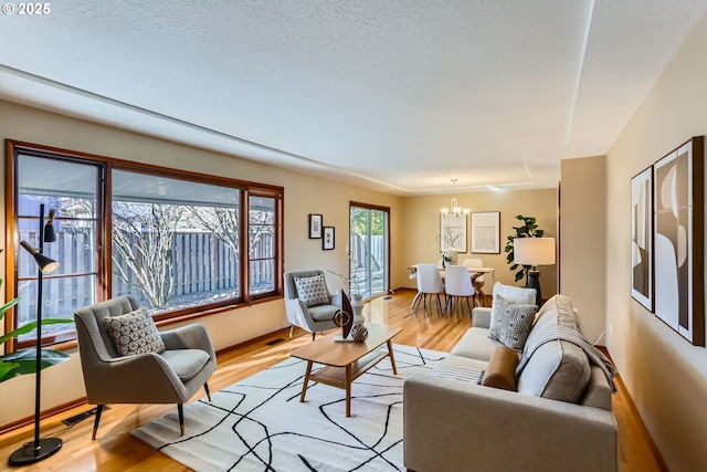 living room featuring a notable chandelier, a textured ceiling, and light hardwood / wood-style flooring