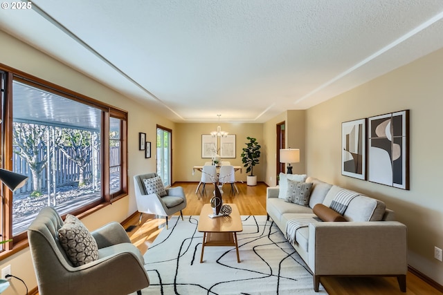 living room featuring a textured ceiling, a chandelier, and light hardwood / wood-style flooring