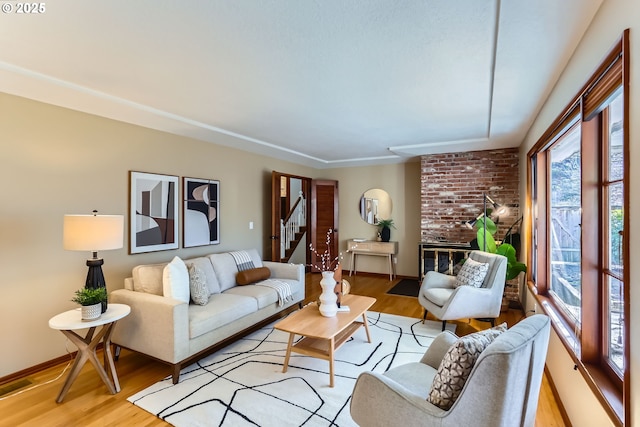 living room with a brick fireplace and light hardwood / wood-style floors