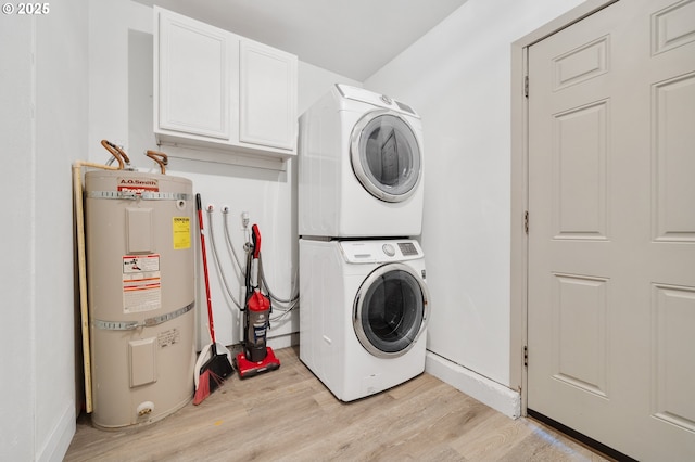 clothes washing area featuring light hardwood / wood-style flooring, stacked washer and clothes dryer, strapped water heater, and cabinets