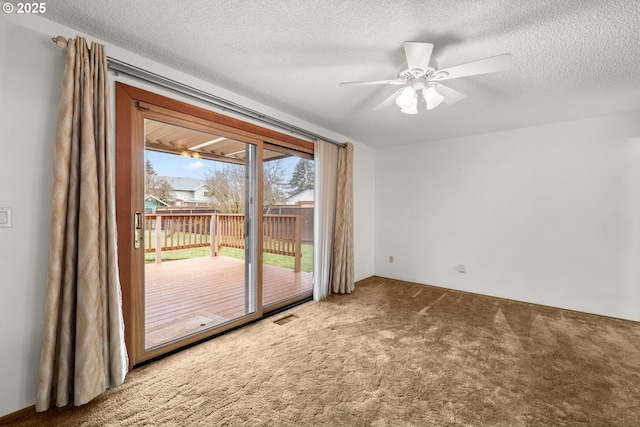 carpeted empty room featuring visible vents, a textured ceiling, and a ceiling fan