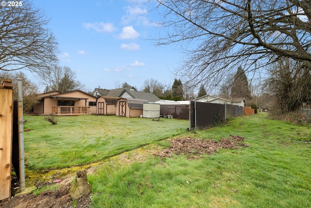 view of yard featuring an outbuilding, a deck, and fence