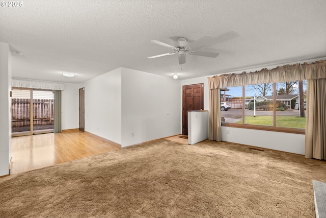 spare room featuring light carpet, a textured ceiling, and a ceiling fan