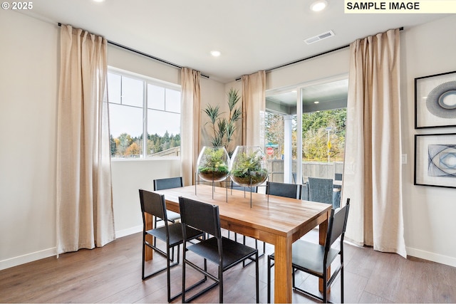 dining area with wood finished floors, visible vents, and baseboards