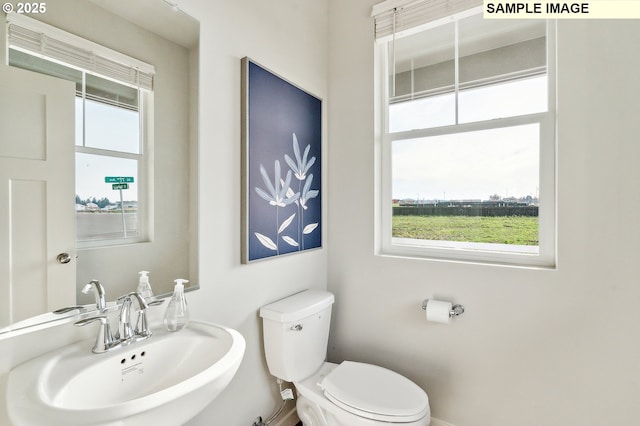 bathroom featuring baseboards, toilet, and a sink