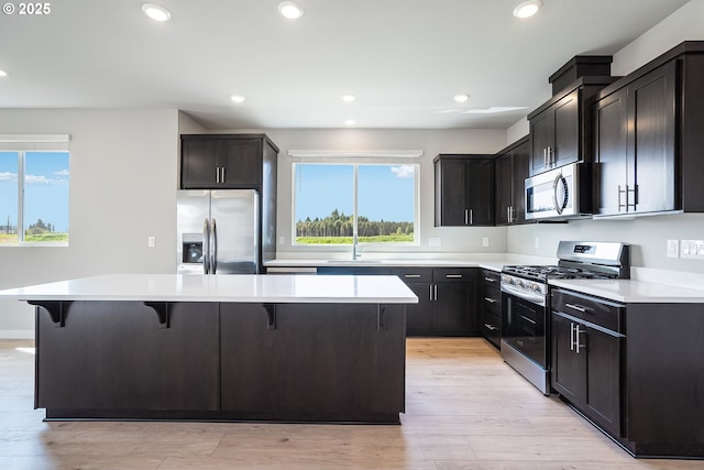 kitchen featuring a center island, a kitchen bar, stainless steel appliances, and plenty of natural light