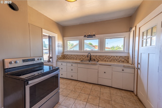 kitchen featuring electric stove, tasteful backsplash, white cabinetry, and a sink