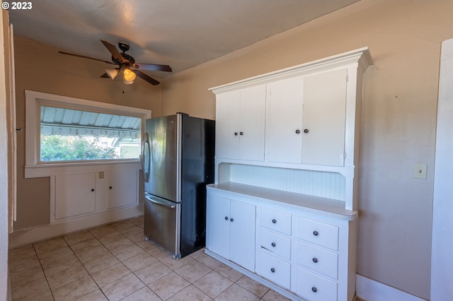 kitchen with freestanding refrigerator, light tile patterned floors, light countertops, white cabinets, and a ceiling fan