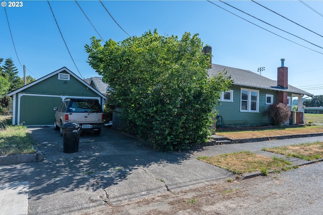 view of front of property with a chimney, a garage, and an outbuilding