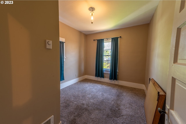 carpeted empty room featuring baseboards