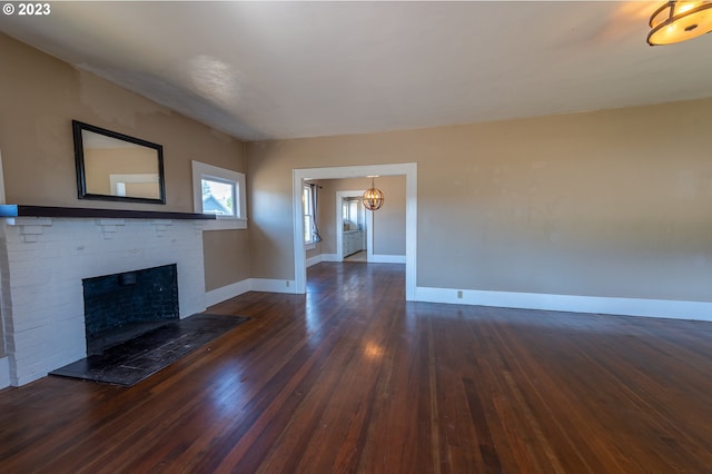 unfurnished living room with a fireplace, wood finished floors, a notable chandelier, and baseboards