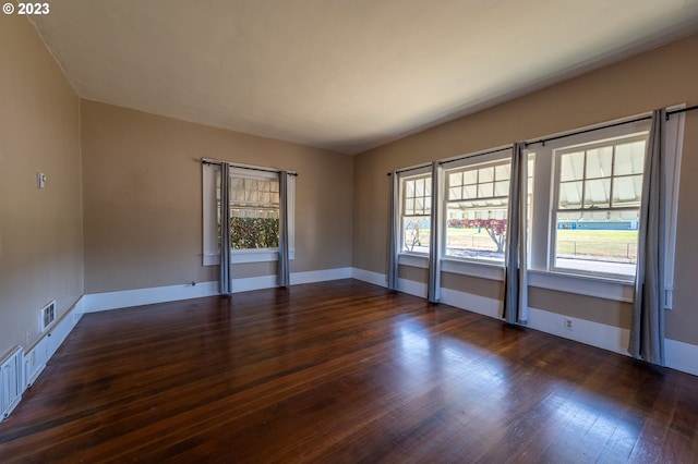 unfurnished room featuring visible vents, wood finished floors, and baseboards