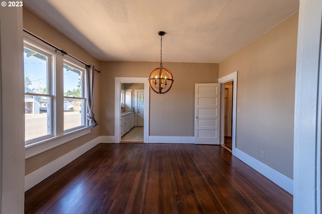 unfurnished dining area with an inviting chandelier, plenty of natural light, dark wood-style floors, and baseboards