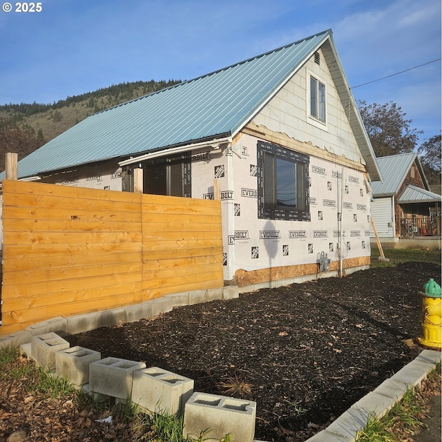 view of property exterior with fence and metal roof